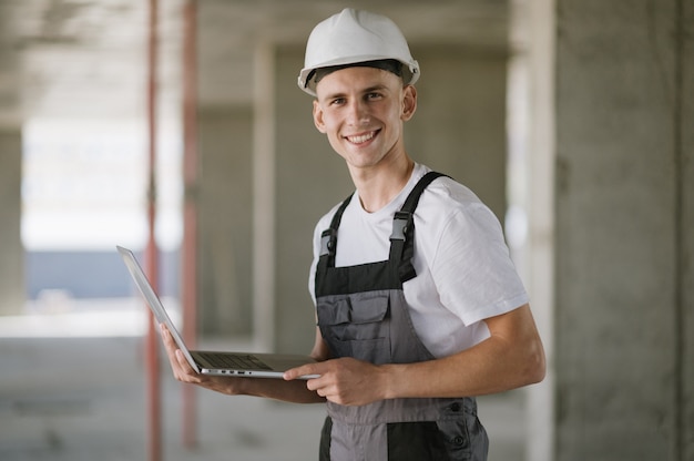 Arbeiter im Schutzhelm, der am Laptop arbeitet