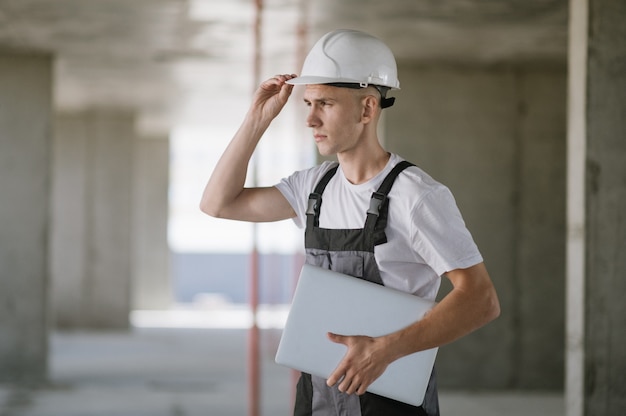 Arbeiter im Schutzhelm, der am Laptop arbeitet