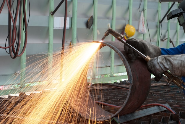 Arbeiter in der Fabrik schneiden Stahlrohr mit Metall Taschenlampe