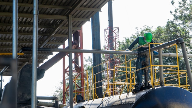 Foto arbeiter in der ölrecyclingindustrie überprüft lagertanks