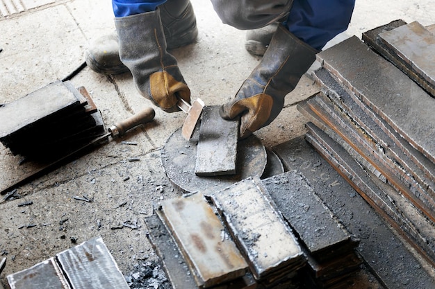 Arbeiter in der Schwerindustrie oder Metallurgie schlägt Eisenplatten mit Hammer ab Arbeiten mit Metall Authentischer Arbeitsablauf