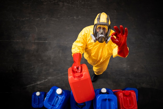 arbeiter in hazmat-schutzanzug und gasmaske, der mit gefährlichen chemikalien in der fabrik arbeitet