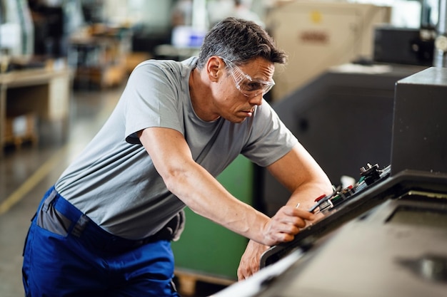 Arbeiter in Industrieanlagen mittleren Alters an einer CNC-Maschine