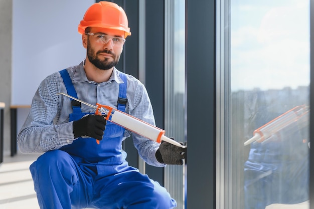 Arbeiter in Overalls, die Plastikfenster im Wohnzimmer zu Hause installieren oder einstellen