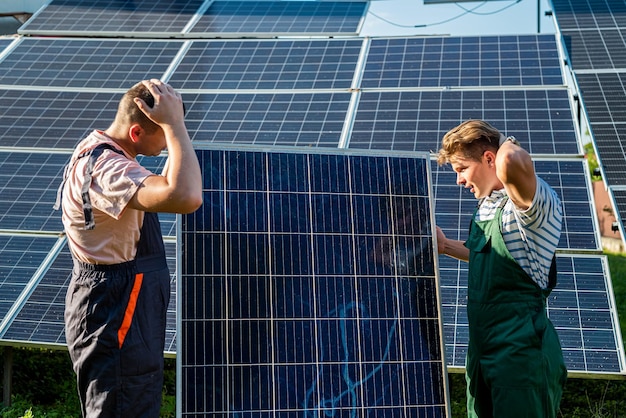 Arbeiter in Schutzuniform mit Solarpanel zur Installation an der neuen Station