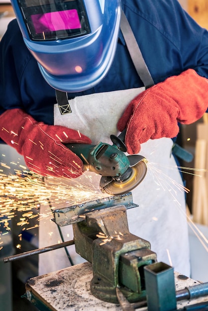 Arbeiter in Spezialkleidung und Schutzbrille beim Schleifen von Metall mit Kreissägenwerkstatt