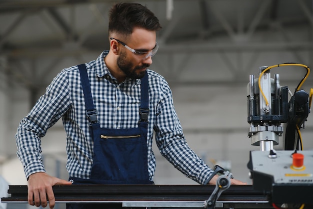 Arbeiter in Uniform, der an der Maschine im PVC-Shop im Innenbereich arbeitet