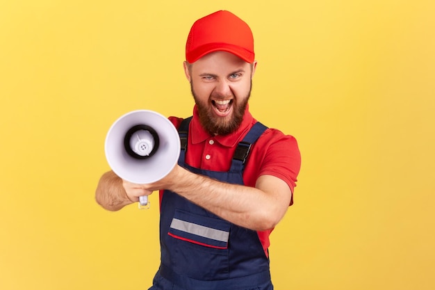 Arbeiter Mann hält Megaphon und blickt mit finsterem Gesicht in die Kamera