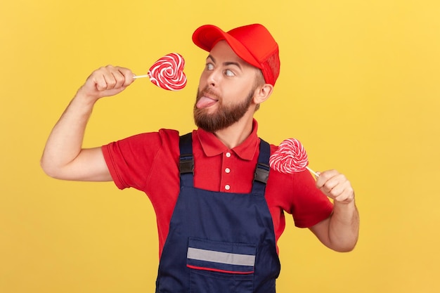 Arbeiter Mann mit leckeren zuckerhaltigen Süßigkeiten lecken Herzform Lollypop Zunge heraus