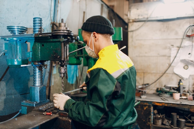 Arbeiter mit Bohrmaschine arbeitet an Metallfabrik