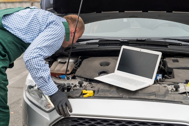 Arbeiter mit Laptop, der Diagnose des Automotors macht