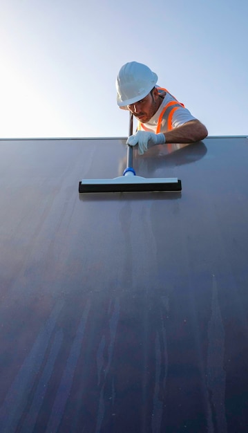 arbeiter mit persönlicher schutzausrüstung, der sonnenkollektoren reinigt