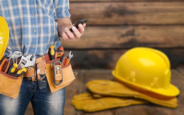 Arbeiter mit Werkzeuggürtel auf Holzuntergrund.