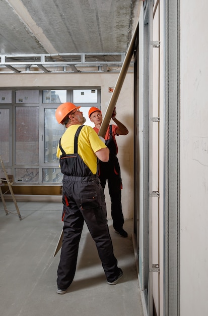 Arbeiter montieren eine Gipskartonplatte an der Wand