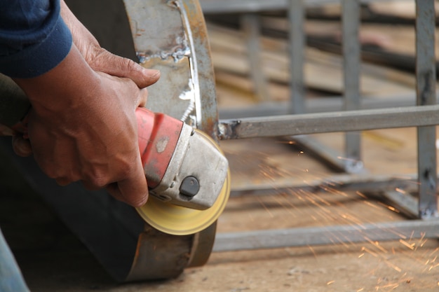 Arbeiter sägen Metall mit einem Schleifer, Funken fliegen