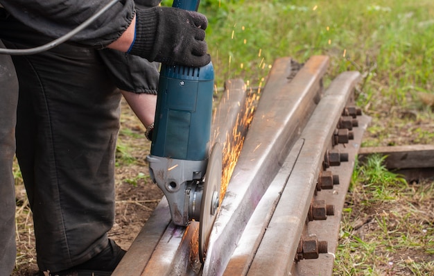 Arbeiter schneiden Metallprodukte für die Wartung der Eisenbahn, Funken fliegen