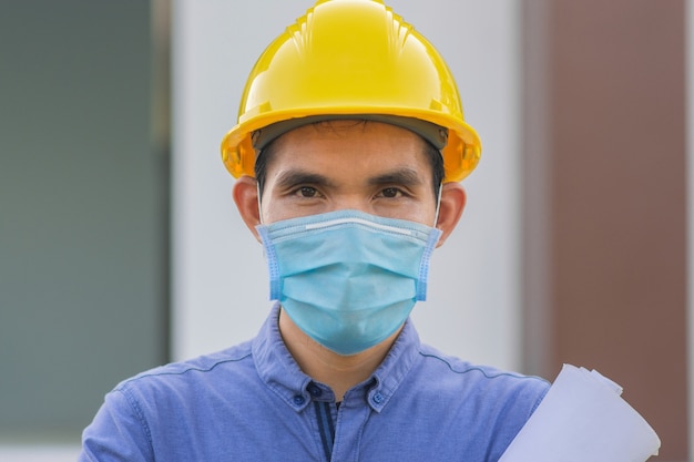 Arbeiter tragen Gesichtsmaske, die auf der Baustelle arbeitet, Mann trägt Maske zum Schutz von Coronavirus covid19