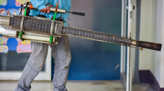 Arbeiter versprühen Moskito-Pestizide mit einem motorisierten SprüherxA