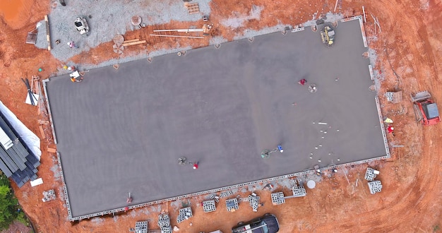 Arbeiter verwenden Betonpoliermaschinen für Zement, nachdem sie Beton auf den Fundamentboden gegossen haben