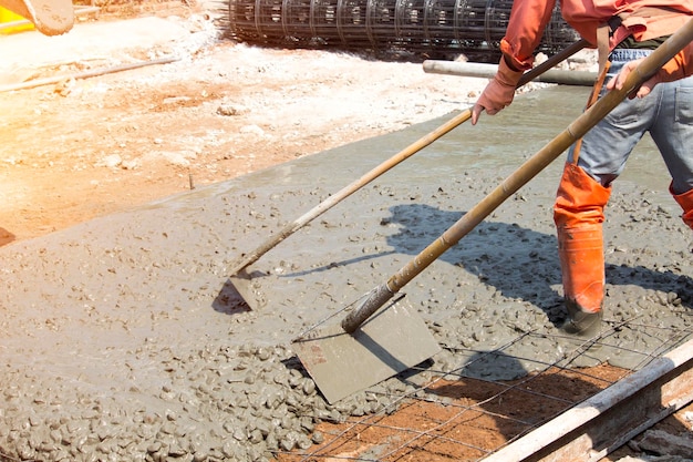 Arbeiter verwenden Werkzeuge, um den Betonboden zu glätten