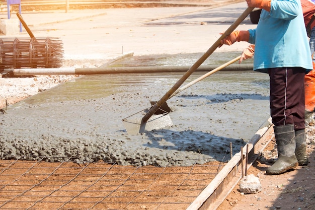 Arbeiter verwenden Werkzeuge, um den Betonboden zu glätten