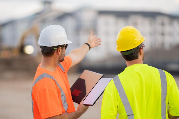 Arbeiter weist auf Bauarbeiter mit Schutzhelm auf Baustelle hin, Ingenieurarbeiter in