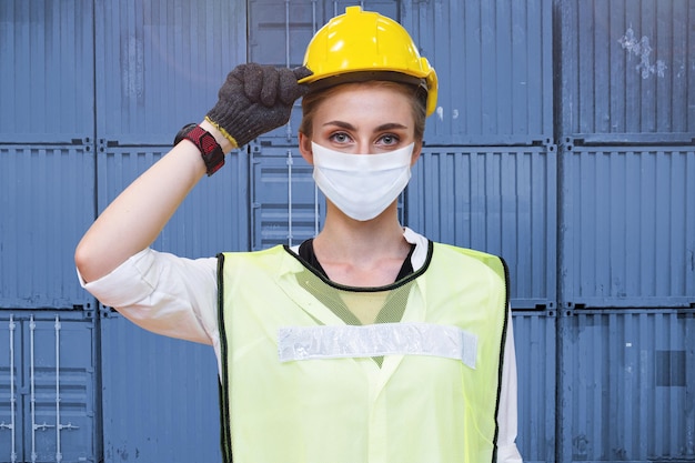 Arbeiterfrauentechnik mit Gesichtsmaske, die selbstbewusst mit Schutzhelm steht