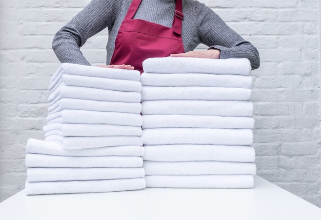 Arbeiterhände halten viele weiße Handtücher in der Wäscherei oder im Hotel auf weißem Hintergrund