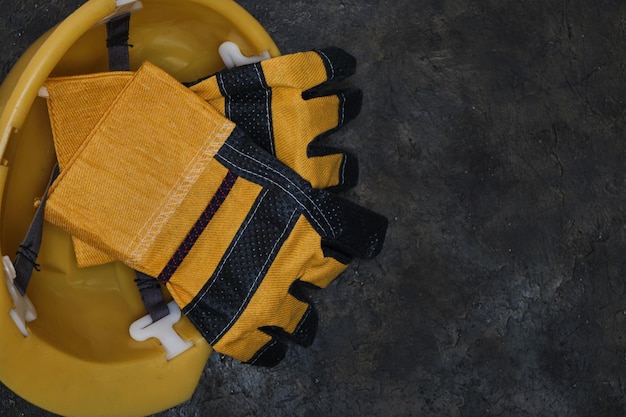 Foto arbeiterhandschuhe und schutzhelm auf konkretem hintergrund.