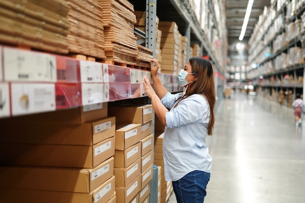 Arbeiterin, die Lagerbestand der Produkte während der Arbeit im großen Lager inspiziert.