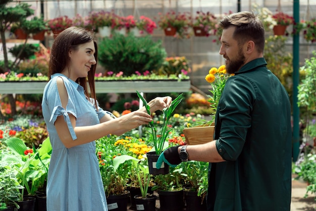 Foto arbeiterin hilft einer kundenin mit einer pflanze im gartenzentrum