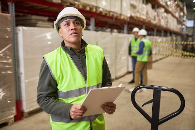 Arbeiterin im Lager blickt auf Regale