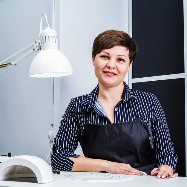 Arbeiterin in einem Nagelstudio am Arbeitsplatz wartet auf einen Kunden