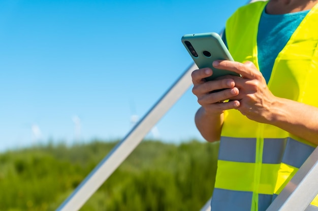 Arbeiterin in einem windpark mit grüner energie, die die notizen mit dem telefon überprüft