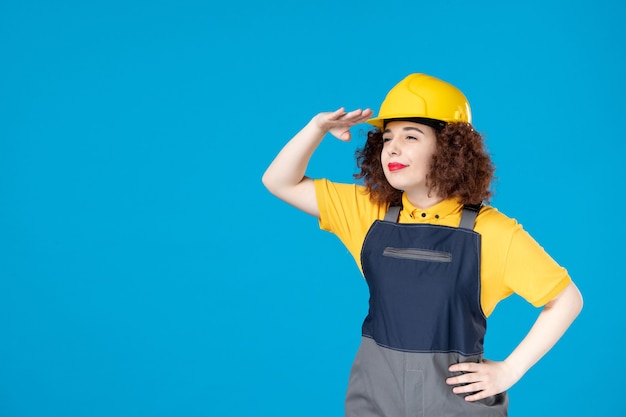 Arbeiterin in gelber Uniform und Helm auf Blau