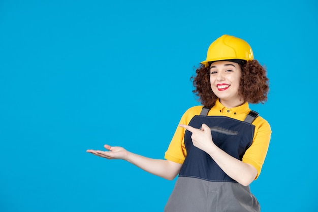 Arbeiterin in gelber Uniform und Helm auf Blau