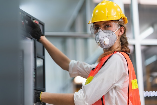 Arbeiterin mit Sicherheitsweste und gelbem Helm bei der Arbeit