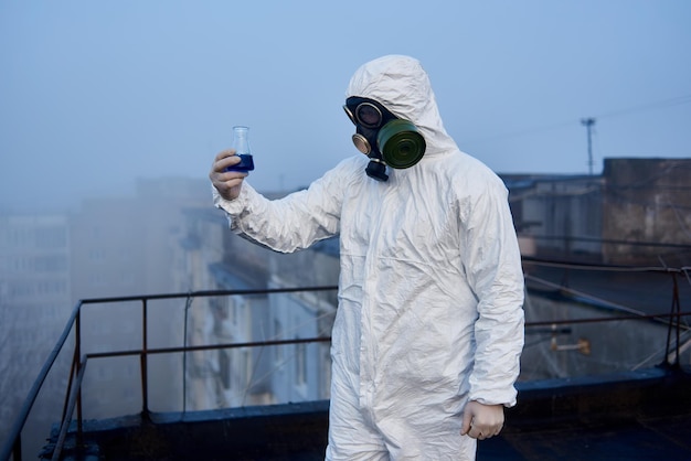 Arbeiterwissenschaftler mit Schutzoverall und Gasmaske bei ökologischen Tests auf dem Dach