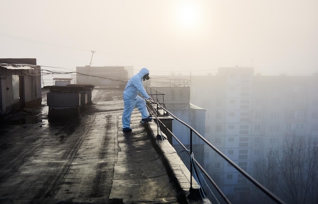 Arbeiterwissenschaftler mit Schutzoverall und Gasmaske bei ökologischen Tests auf dem Dach