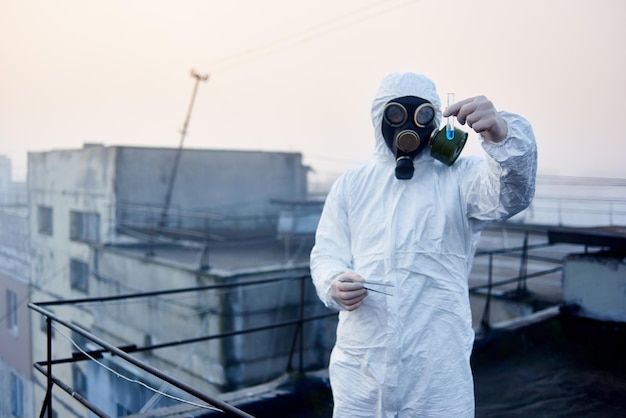 Arbeiterwissenschaftler mit Schutzoverall und Gasmaske bei ökologischen Tests auf dem Dach