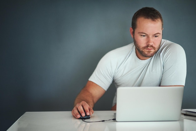 Arbeitet an seinem Blog Schnappschuss eines jungen Mannes, der an seinem Laptop arbeitet