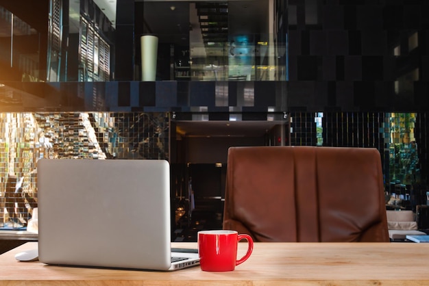 Arbeitsbereich mit Computer-Laptop-Bürobedarf und Kaffeetassen-Smartphone und -Tablet am Schreibtisch-Arbeitskonzept im MorgenlichtxA