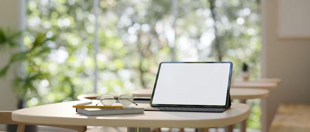 Arbeitsbereich mit Tablet-Modell auf einem Holztisch in einem minimalen Café-Coworking-Bereich