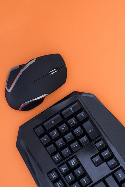 Arbeitsbereich mit Tastatur und Maus auf orangefarbenem Hintergrund. Copyspace