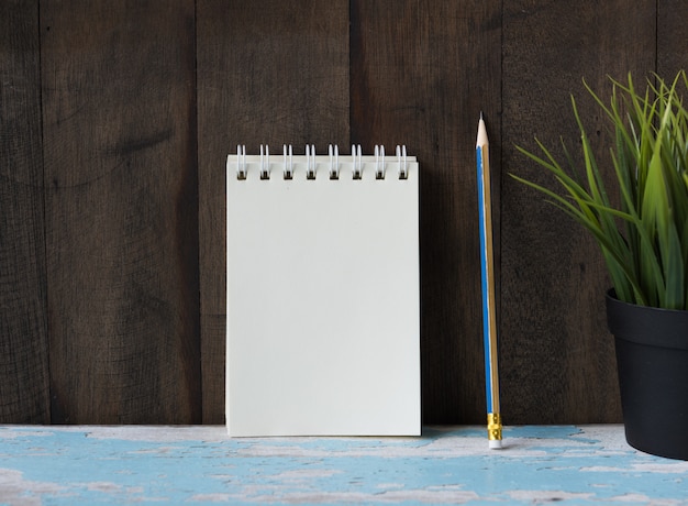 Arbeitsbereich Notizbuch und gelber Stift auf Vintage blauen Holztisch