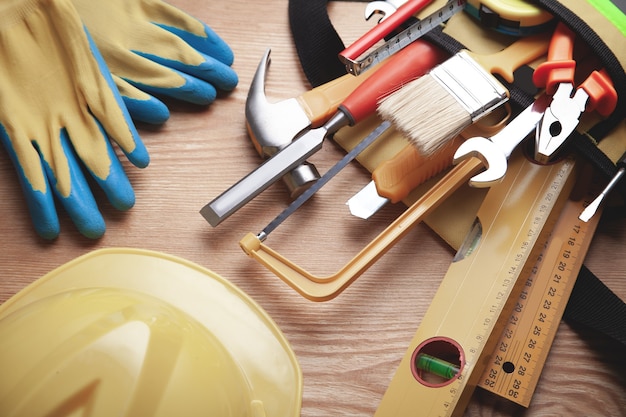 Arbeitsgeräte mit Helm und Handschuhen auf Holzhintergrund.