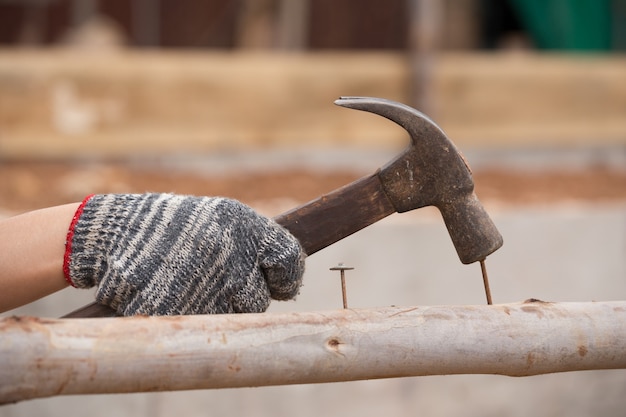 Arbeitskraft, die Nagel in Holz hämmert