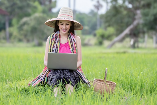 Arbeitslaptop der schönen asiatischen Frau draußen auf den Reisgebieten.