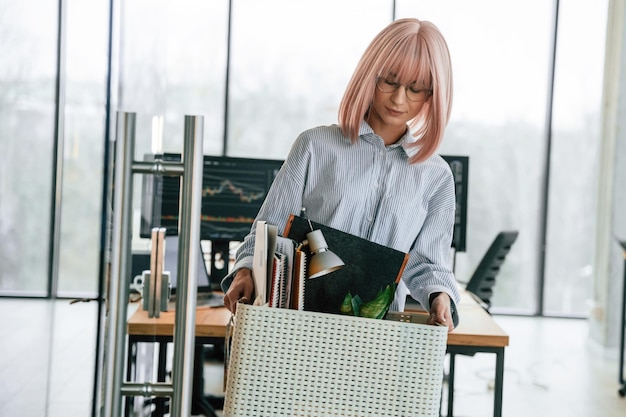 Foto arbeitslose frau mit rosa haaren ist mit persönlichen gegenständen, nachdem sie gefeuert wurde