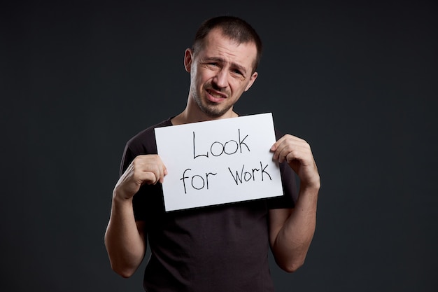 Arbeitslosigkeit und Krise. Mann hält ein Schild mit den Worten Arbeit suchen